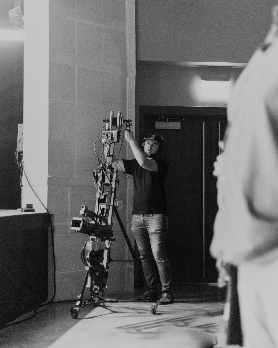Technician adjusting professional video equipment on a rolling stand.
