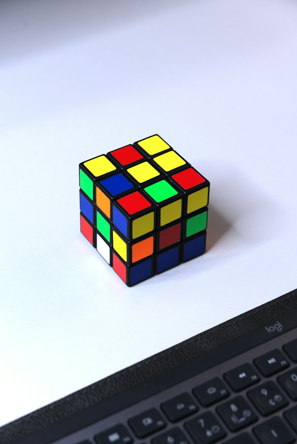 A partially solved Rubik's cube sits near a computer keyboard.